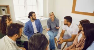 Diverse team of professionals sitting in a circle engaged in an open leadership conversation, illustrating how culture is built through dialogue